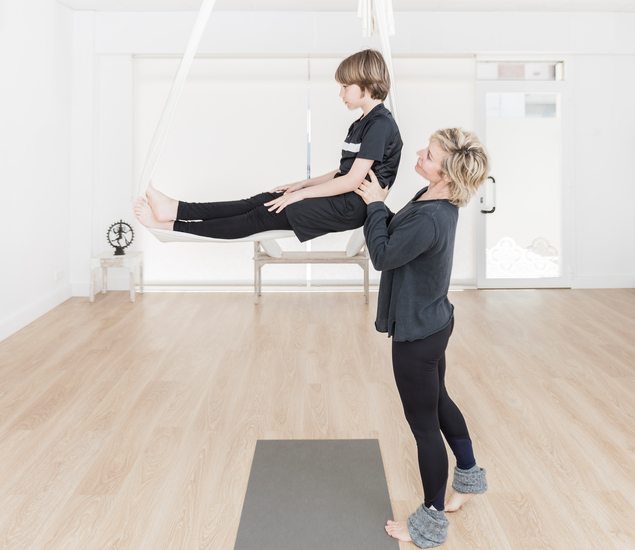 Aerial instructor teaching aerial yoga to child